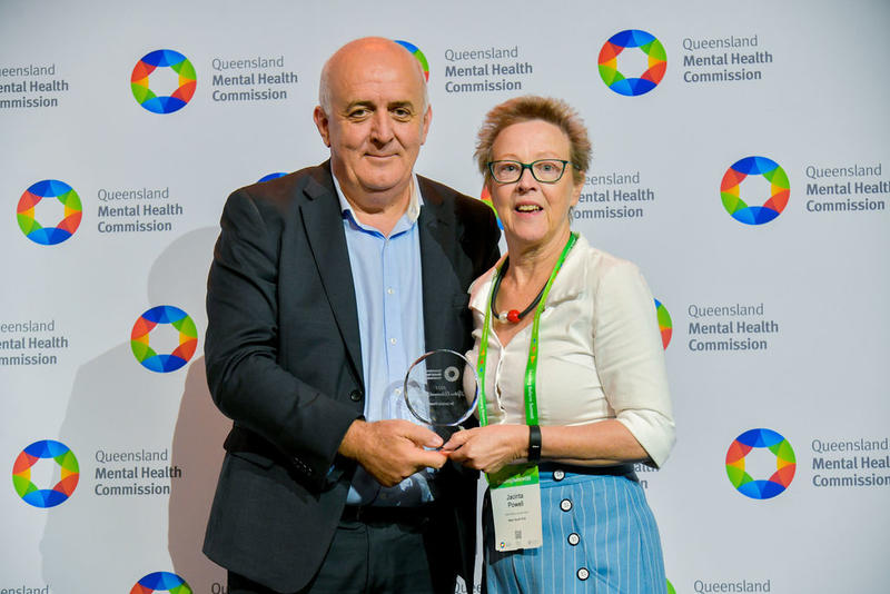 Dr Jacinta Powell standing with Commissioner Ivan Frkovic receiving the award