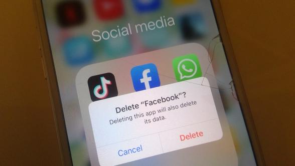 Image of a phone showing social media icons on the screen and a message saying delete facebook?