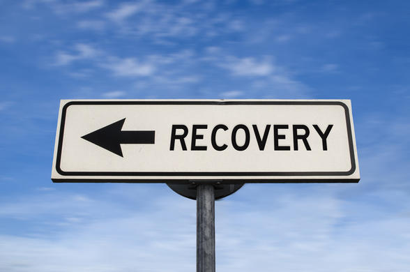 Sign with arrow saying recovery, set against a blue sky 