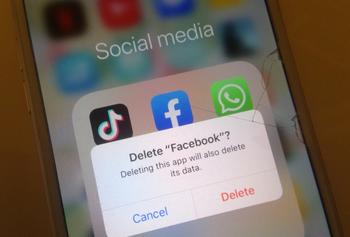 Image of a phone showing social media icons on the screen and a message saying delete facebook?