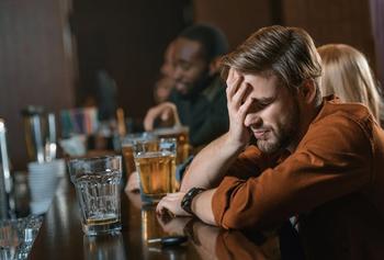 A person clutching his head at a bar.
