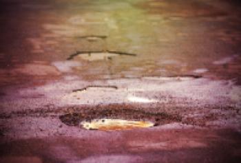 Moody image of wet road with potholes