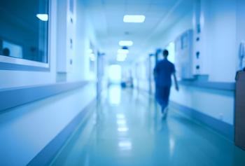 Blurred image of person walking down hospital corridor 